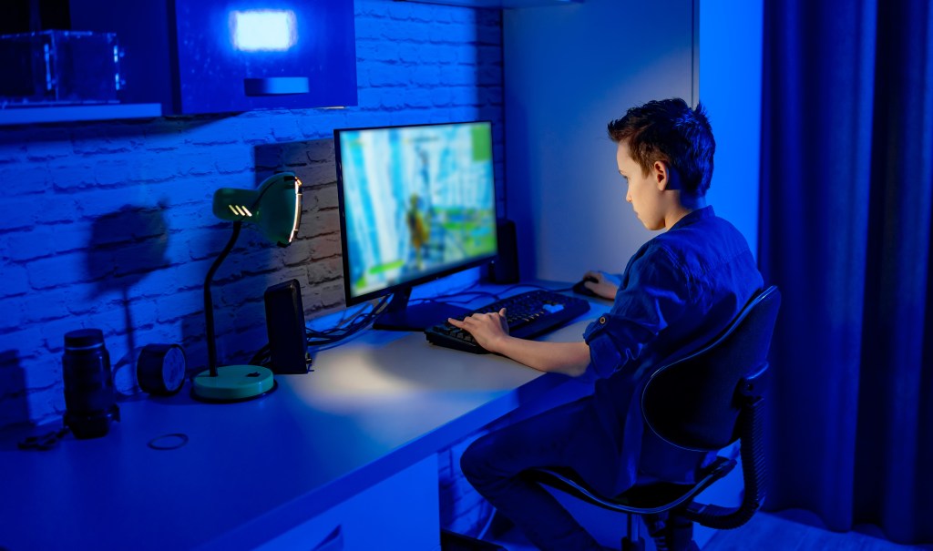 Tween boy sitting at computer playing an online game